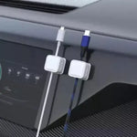 White magnetic cable clips keeping charging cables organized on a car dashboard