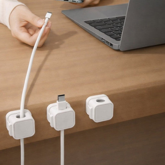 White magnetic cable clips holding a charging cable at a desk